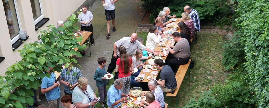 Viele Menschen essen gemeinsam an großem Tisch draußen